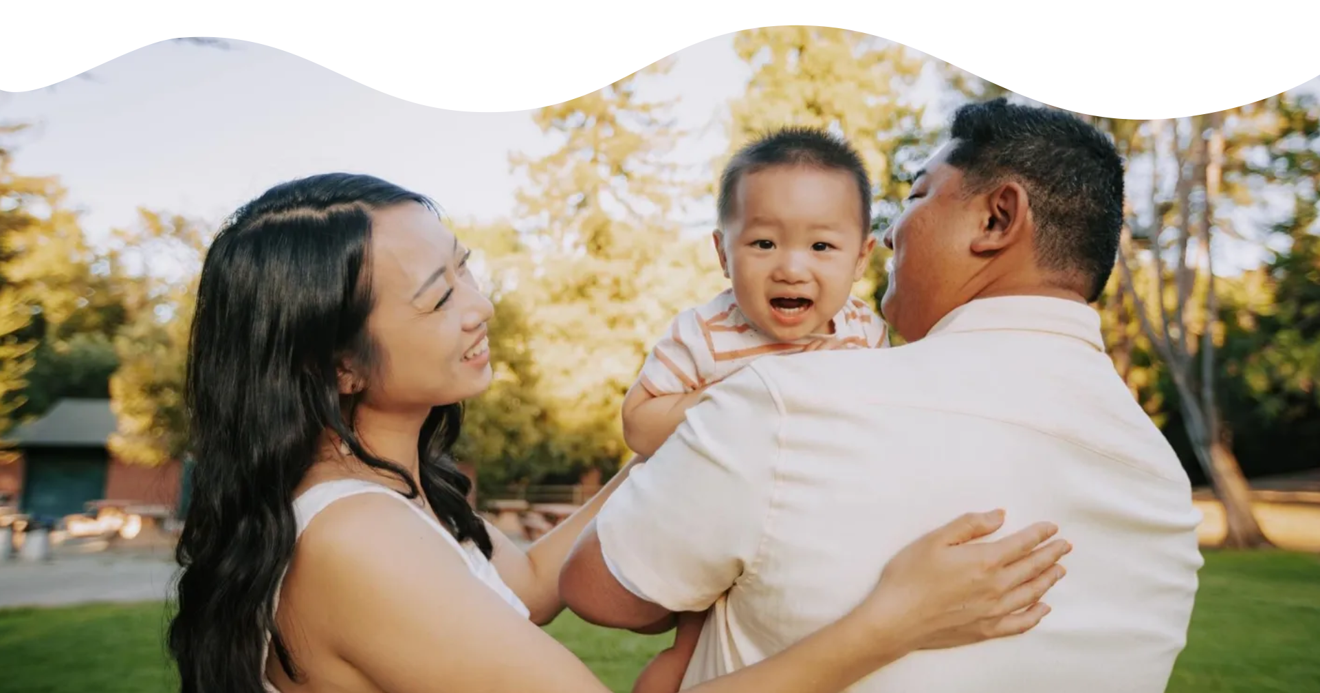 A family is holding their baby in the park.