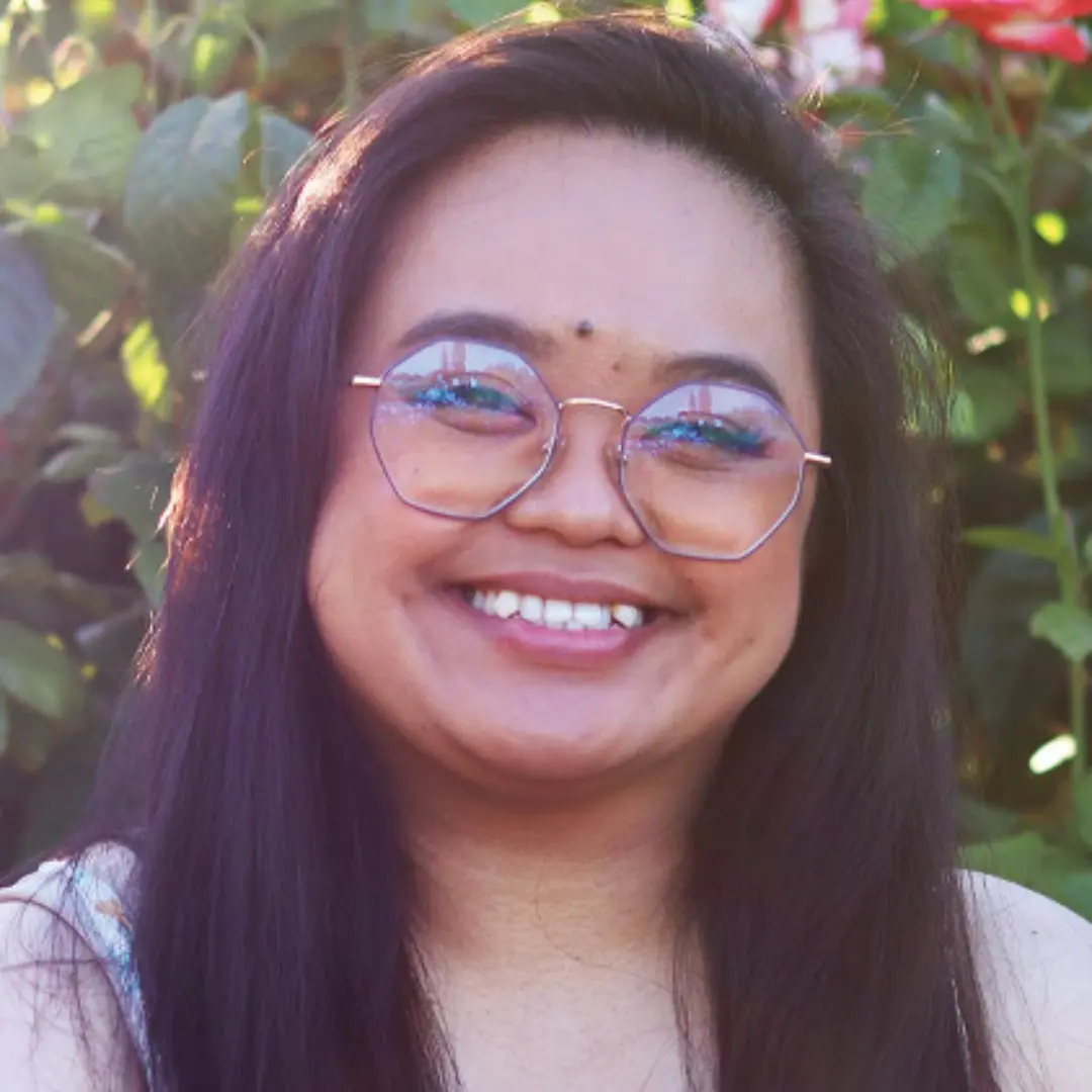 A woman with glasses smiling for the camera.